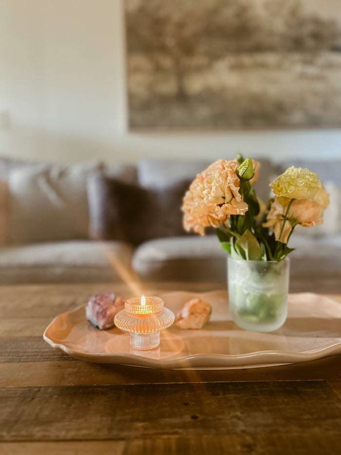 Busy Bees Glass Lantern set of 2 displayed on a wooden coffee table with flowers and soft candlelight in a warm neutral interior.