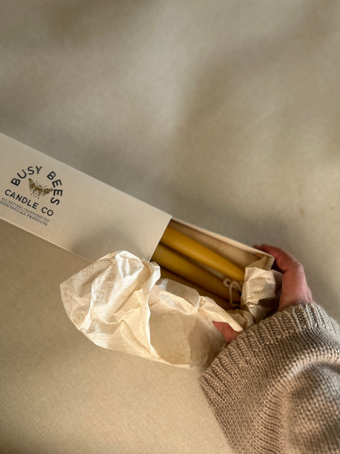 Close up of Busy Bees Hand Dipped 9 Inch Taper Candles 6 Pack being removed from branded packaging in soft natural light.
