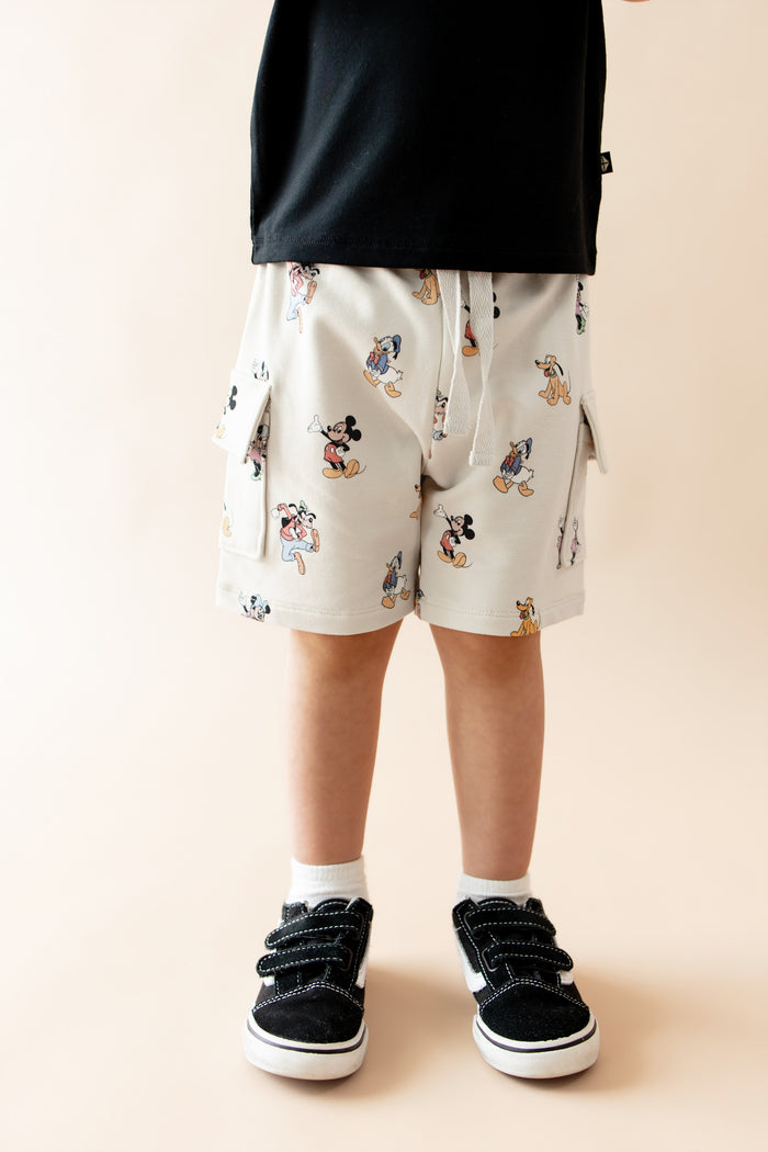child wearing mickey mouse and friends printed cargo shorts and black vans