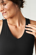 Close up portrait of a woman wearing the Elastique Athletics Adorn Tank in black with a scoop neckline and seamless fit.