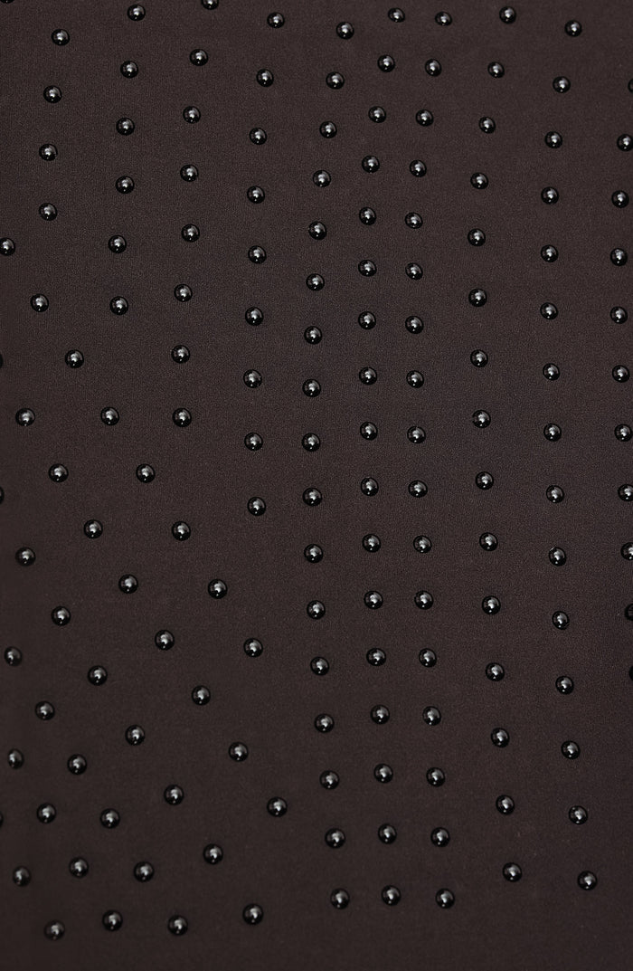 Close up fabric texture detail of the Elastique Athletics Le Monde Bra featuring a subtle dotted grip pattern on dark brown fabric.