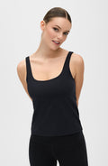 Woman smiling while wearing the Elastique Athletics Lisse Compression Tank in black with matching high waisted leggings against a neutral studio background.
