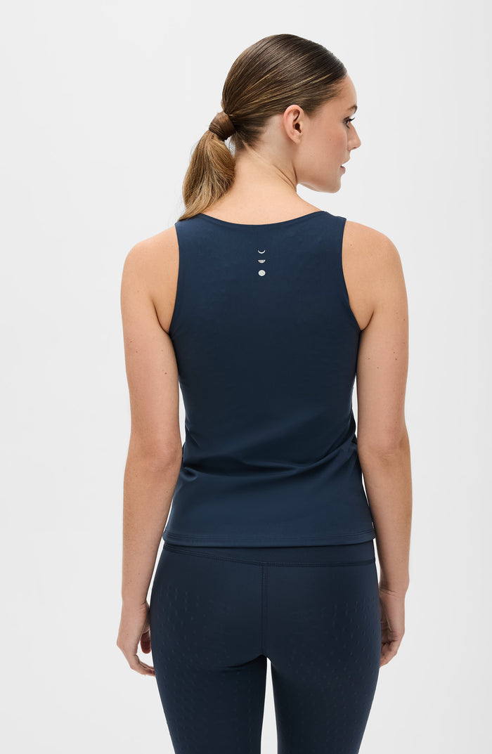 Back view of a woman wearing the Elastique Athletics L'Original Lymphatic Tank in navy blue with matching leggings.
