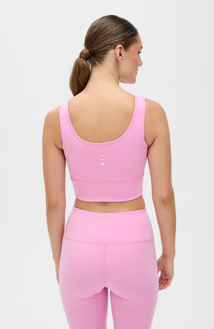 Back view of a woman wearing the Elastique Athletics Rise Bra Vie en Rose in soft pink with matching leggings.