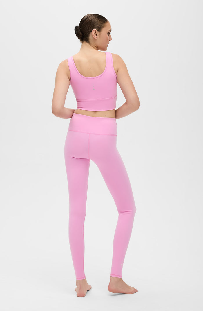 Back view of a woman wearing the Elastique Athletics Rise Leggings Vie en Rose in soft pink with a matching sports bra.