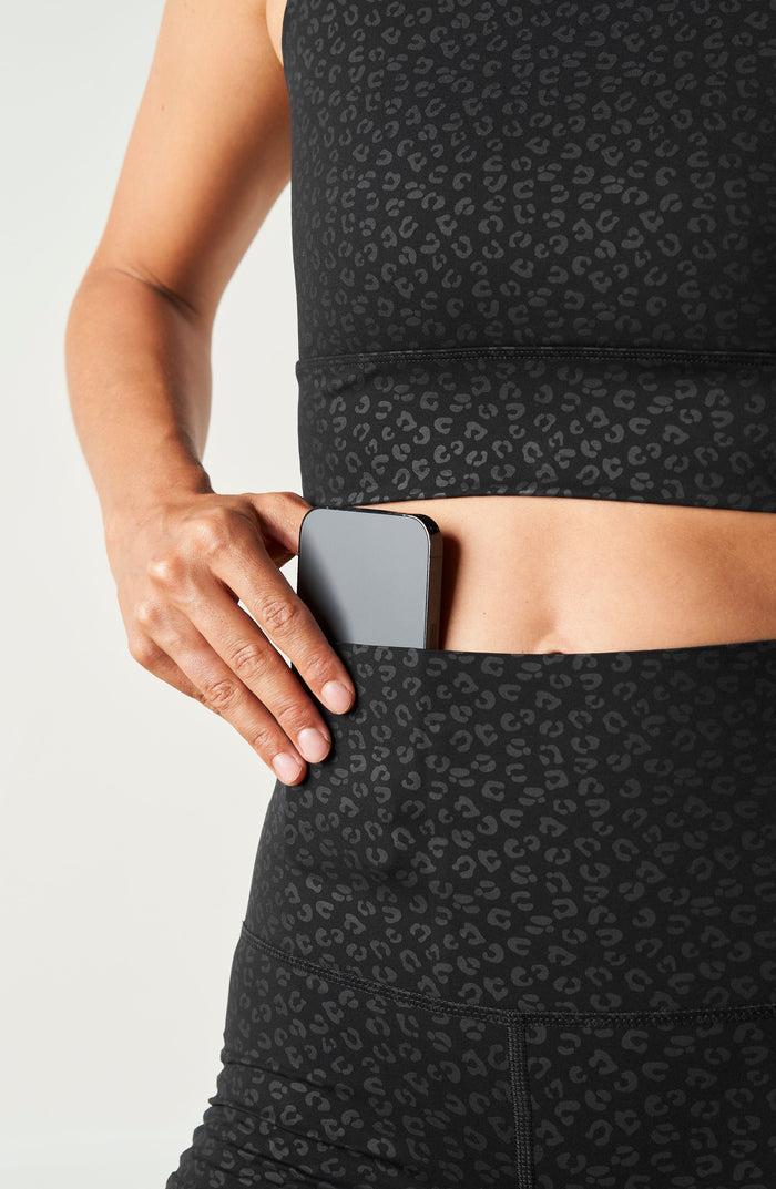 Close up waistband detail of the Elastique Athletics The Fierce Bra in black paired with matching textured leggings.