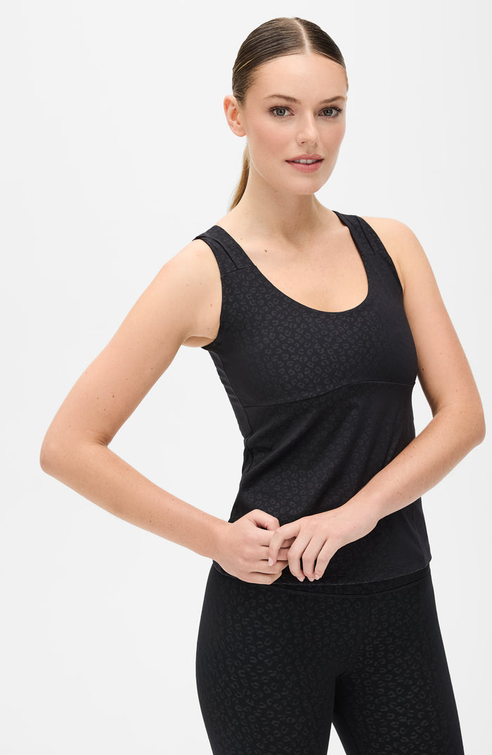 Full body studio portrait of a woman wearing the Elastique Athletics The Fierce Tank in black with matching leggings.