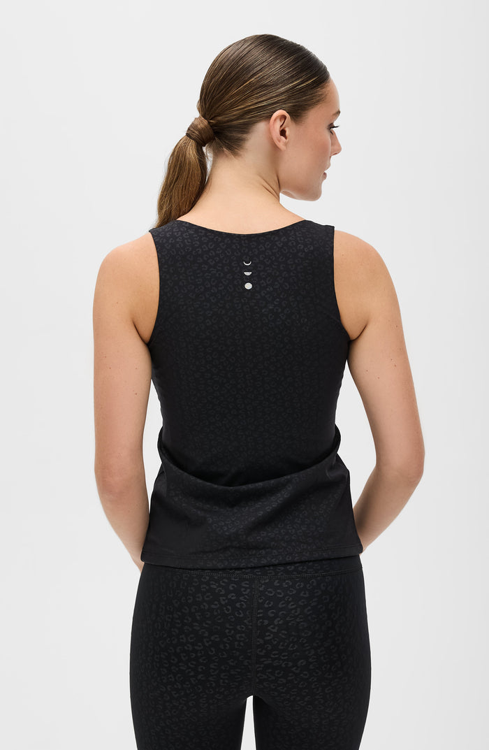 Back view of a woman wearing the Elastique Athletics The Fierce Tank in black with a racerback silhouette and matching leggings.