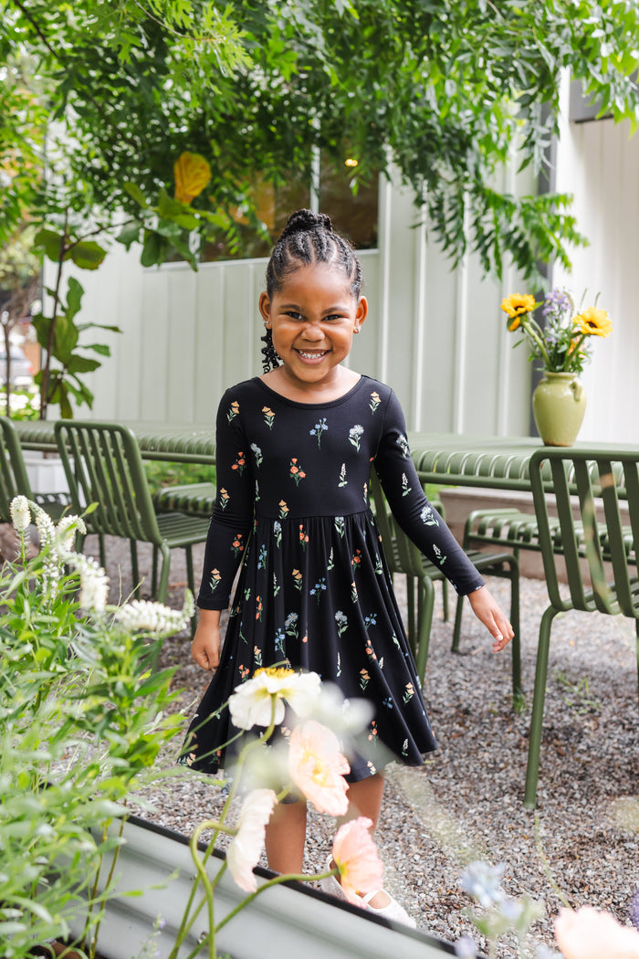 Girl smiling outdoors under a tree wearing Long Sleeve Twirl Dress in Midnight Wildflower print