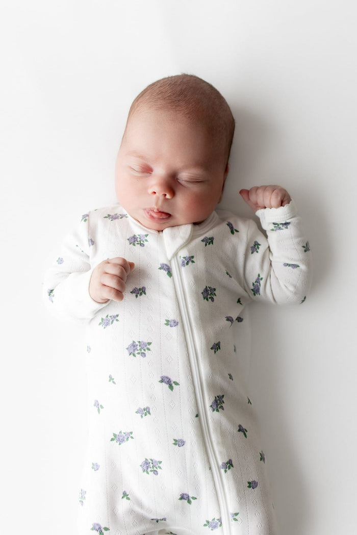 Close up of sleeping newborn wearing the Pointelle Zippered Footie in Spray Rose