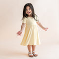 Child wearing a light yellow short sleeve twirl dress