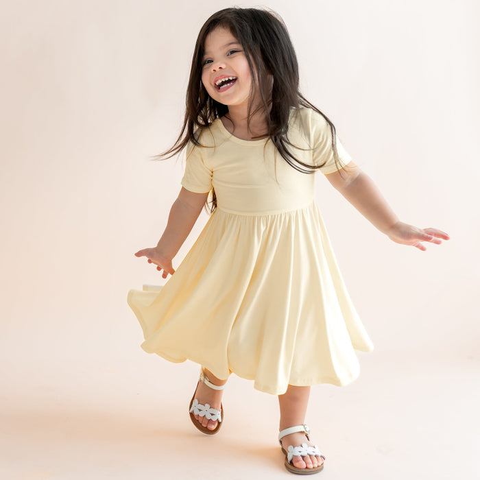 Child in a yellow dress standing on a light background