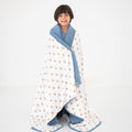 Child wrapped in a teddy bear pattern blanket with blue trim on a white background
