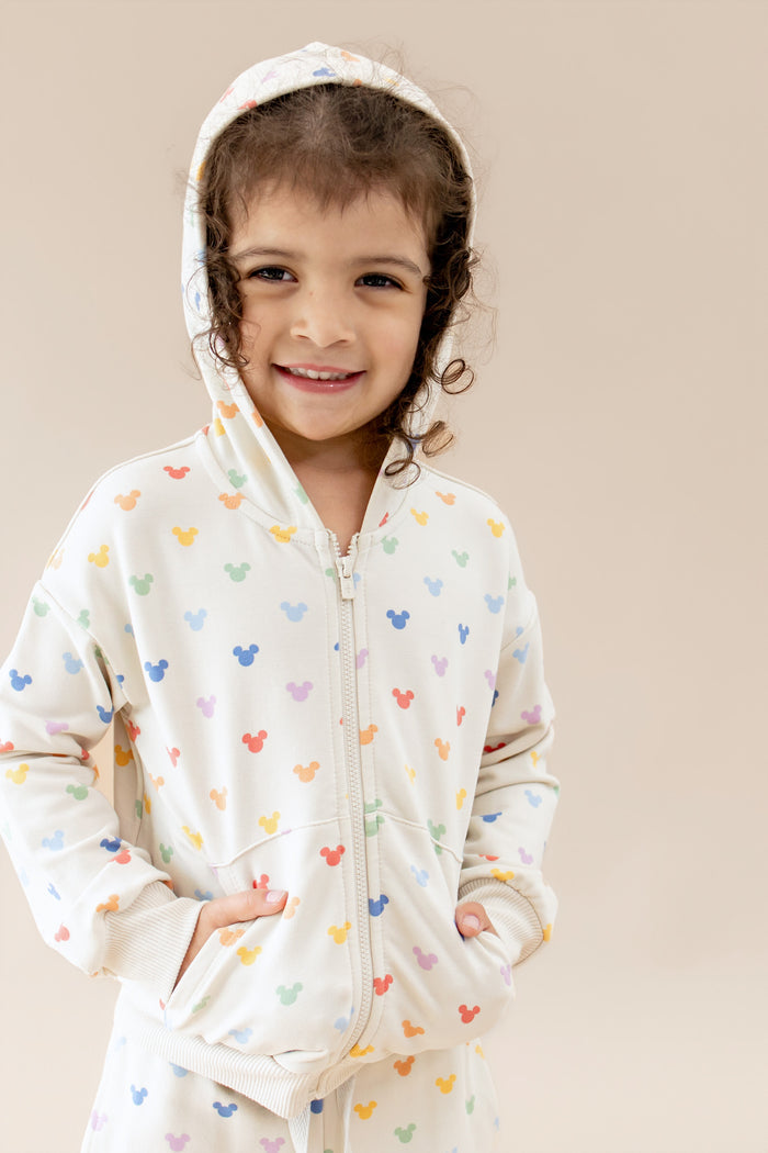 Child wearing a zip up hoodie with a colorful mickey pattern
